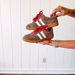 Mini leopard print sneakers with white stripes on the sides and contrasting red laces.