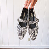 Cream and black zebra print ballet flat with pointed tow, Mary Jane style buckle across the top and silver rivet holes throughout.