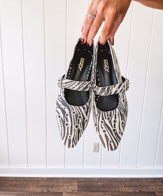 Cream and black zebra print ballet flat with pointed tow, Mary Jane style buckle across the top and silver rivet holes throughout.