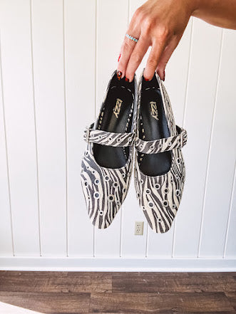 Cream and black zebra print ballet flat with pointed tow, Mary Jane style buckle across the top and silver rivet holes throughout.