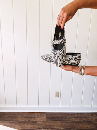 Cream and black zebra print ballet flat with pointed tow, Mary Jane style buckle across the top and silver rivet holes throughout.