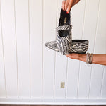 Cream and black zebra print ballet flat with pointed tow, Mary Jane style buckle across the top and silver rivet holes throughout.