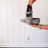 Cream and black zebra print ballet flat with pointed tow, Mary Jane style buckle across the top and silver rivet holes throughout.