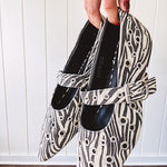 Cream and black zebra print ballet flat with pointed tow, Mary Jane style buckle across the top and silver rivet holes throughout.