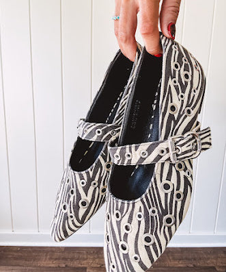 Cream and black zebra print ballet flat with pointed tow, Mary Jane style buckle across the top and silver rivet holes throughout.