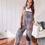 Washed black and pink patchwork jumpsuit with leo and floral print throughout, wide leg design, raw hems, adjustable straps and sides.