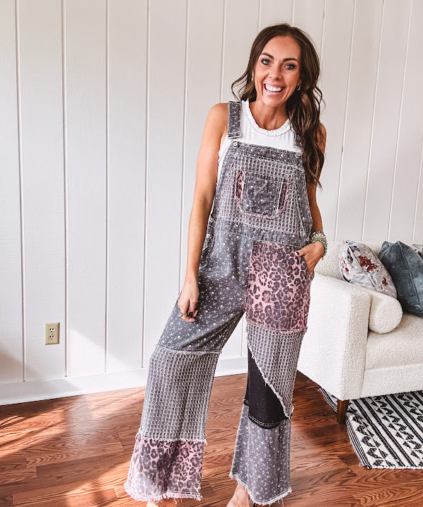 Washed black and pink patchwork jumpsuit with leo and floral print throughout, wide leg design, raw hems, adjustable straps and sides.