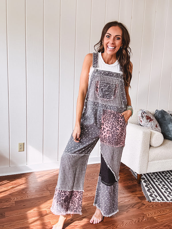 Washed black and pink patchwork jumpsuit with leo and floral print throughout, wide leg design, raw hems, adjustable straps and sides.