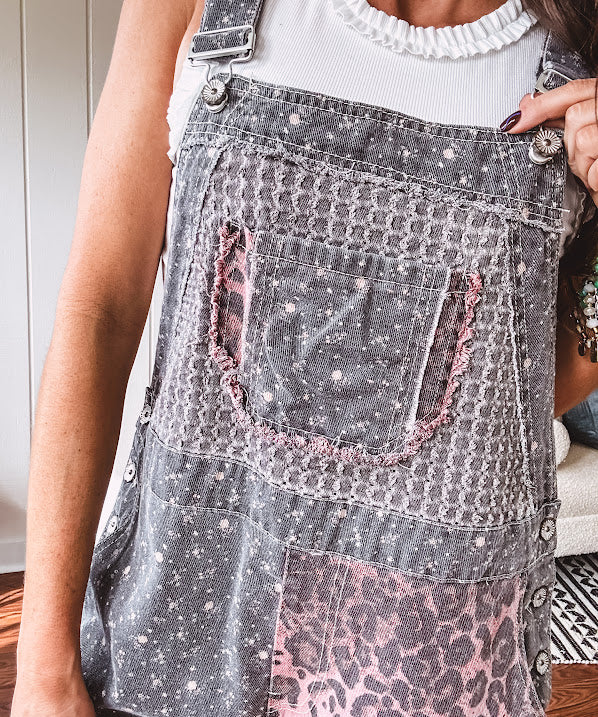 Washed black and pink patchwork jumpsuit with leo and floral print throughout, wide leg design, raw hems, adjustable straps and sides.