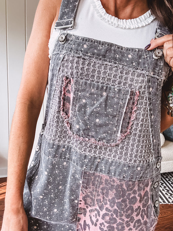 Washed black and pink patchwork jumpsuit with leo and floral print throughout, wide leg design, raw hems, adjustable straps and sides.