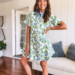 Cream shirt dress with blue and green floral print throughout, contrasting blue trim at the covered placket and hem, cuffed sleeves, mini length, fully lined.
