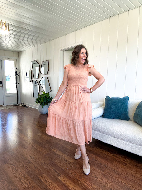 Apricot midi dress with smocked bodice, ruffle sleeves and tiered lined skirt.