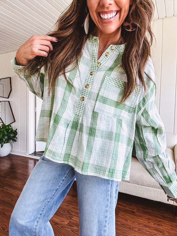 Light apple green and white plaid and gingham print long sleeved top with 1/4 wooden button down front and pleat at placket.