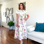 Crisp white button down shirt dress with collar, puffed short sleeves, matching belt and lined skirt featuring spring floral print.