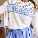 Cream mixed woven sweater with long sleeves and blue "BEACH" woven into the front with matching blue trim on the cuffs.