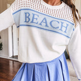Cream mixed woven sweater with long sleeves and blue "BEACH" woven into the front with matching blue trim on the cuffs.