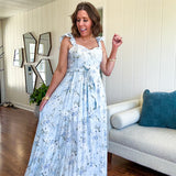 Light blue midi dress with white and green muted florals throughout featuring a bustier bodice, stretchy flutter straps, matching belt and fully lined skirt with slits.