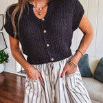 Textured black woven sweater tank with faux wooden buttons down the front and a V neck and hem.