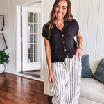 Textured black woven sweater tank with faux wooden buttons down the front and a V neck and hem.