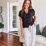 Textured black woven sweater tank with faux wooden buttons down the front and a V neck and hem.