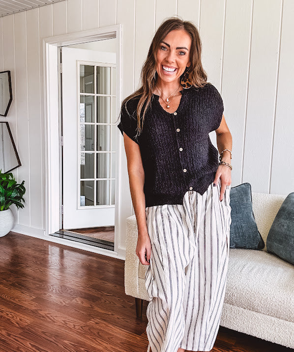 Textured black woven sweater tank with faux wooden buttons down the front and a V neck and hem.