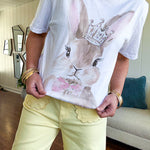 Soft cotton cream colored tee featuring a large brown rabbit with pink accents and rhinestones on the crown and bow.