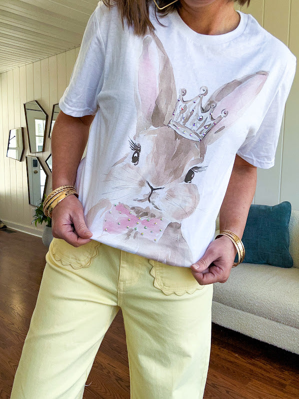 Soft cotton cream colored tee featuring a large brown rabbit with pink accents and rhinestones on the crown and bow.