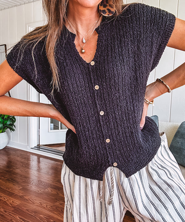Textured black woven sweater tank with faux wooden buttons down the front and a V neck and hem.