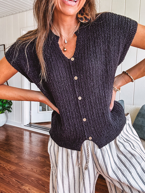 Textured black woven sweater tank with faux wooden buttons down the front and a V neck and hem.