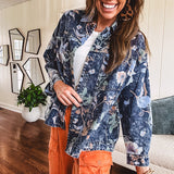 Dark navy washed denim jacket with snap button front and pastel floral print throughout.
