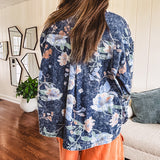 Dark navy washed denim jacket with snap button front and pastel floral print throughout.