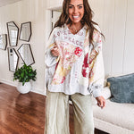 Light grey and cream hoodie with V neck, pink and yellow floral patchwork and retro graphics, split high/low hem.