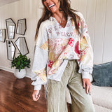 Light grey and cream hoodie with V neck, pink and yellow floral patchwork and retro graphics, split high/low hem.