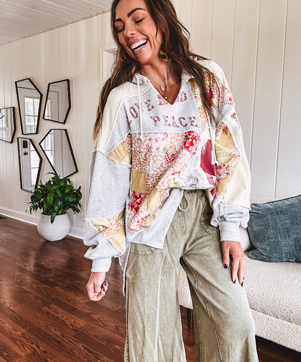 Light grey and cream hoodie with V neck, pink and yellow floral patchwork and retro graphics, split high/low hem.