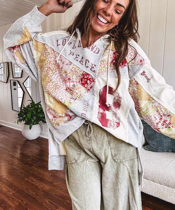 Light grey and cream hoodie with V neck, pink and yellow floral patchwork and retro graphics, split high/low hem.