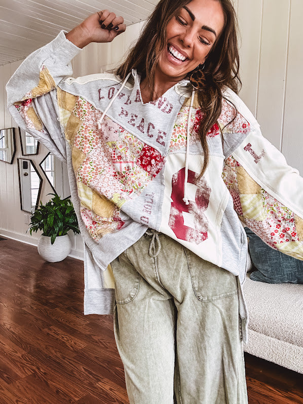 Light grey and cream hoodie with V neck, pink and yellow floral patchwork and retro graphics, split high/low hem.