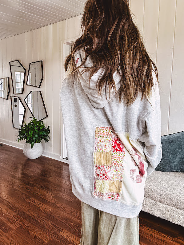 Light grey and cream hoodie with V neck, pink and yellow floral patchwork and retro graphics, split high/low hem.