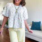 Cream textured flowy fabric with small pink florals throughout with pintuck yoke, puffed short sleeves, zip up back and wide, flowy hem.