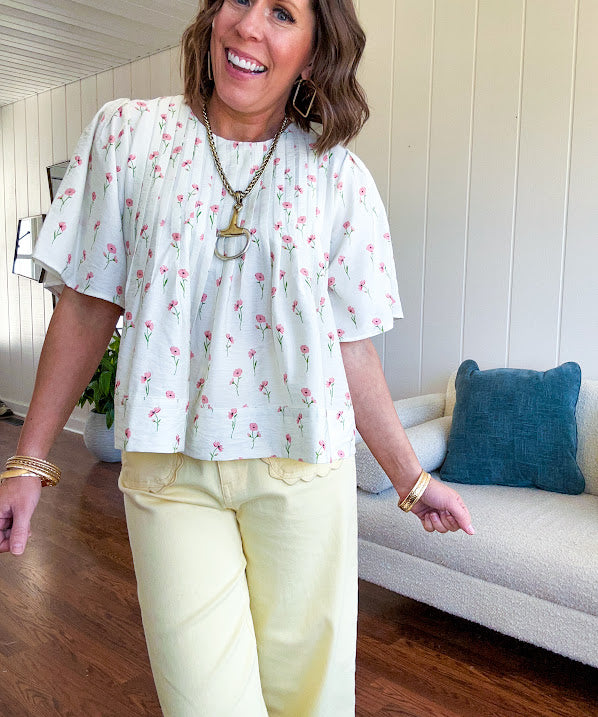 Cream textured flowy fabric with small pink florals throughout with pintuck yoke, puffed short sleeves, zip up back and wide, flowy hem.