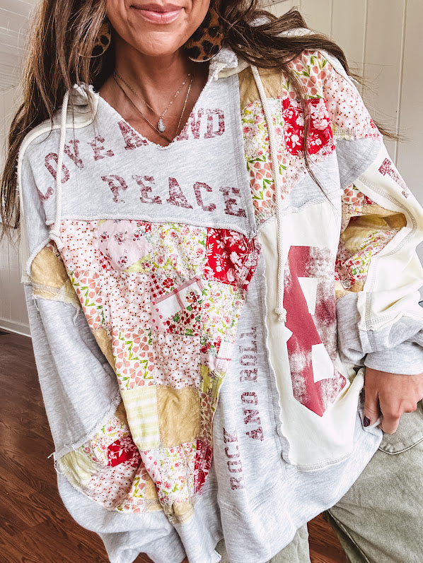 Light grey and cream hoodie with V neck, pink and yellow floral patchwork and retro graphics, split high/low hem.