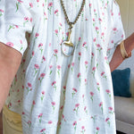 Cream textured flowy fabric with small pink florals throughout with pintuck yoke, puffed short sleeves, zip up back and wide, flowy hem.