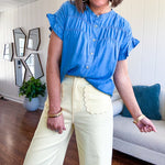 Lightweight medium blue chambray button down top with shirred yoke and ruffled short sleeves.