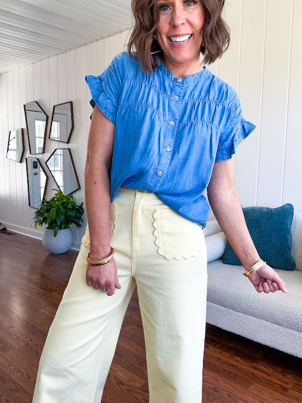 Lightweight medium blue chambray button down top with shirred yoke and ruffled short sleeves.
