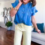 Lightweight medium blue chambray button down top with shirred yoke and ruffled short sleeves.