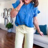 Lightweight medium blue chambray button down top with shirred yoke and ruffled short sleeves.