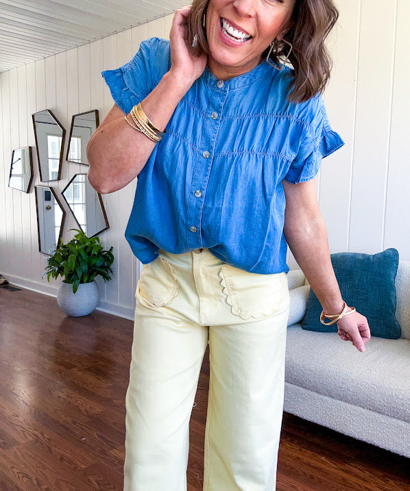 Lightweight medium blue chambray button down top with shirred yoke and ruffled short sleeves.