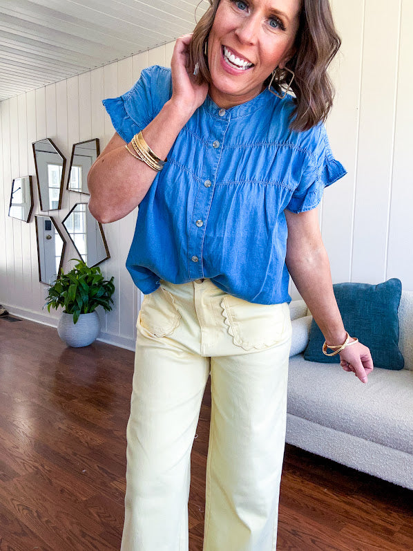 Lightweight medium blue chambray button down top with shirred yoke and ruffled short sleeves.