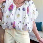 Cream bubble hem blouse with bubble sleeves, pink and yellow florals throughout, V neck and sheer outer layer.