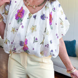 Cream bubble hem blouse with bubble sleeves, pink and yellow florals throughout, V neck and sheer outer layer.