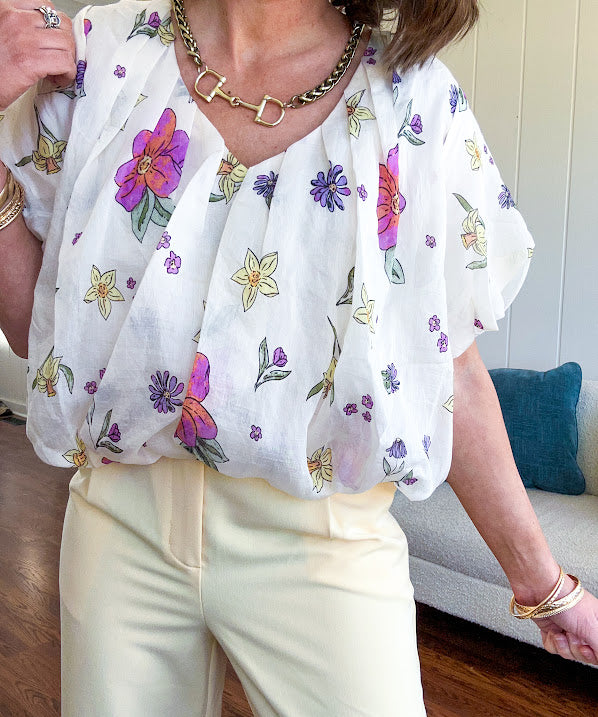 Cream bubble hem blouse with bubble sleeves, pink and yellow florals throughout, V neck and sheer outer layer.
